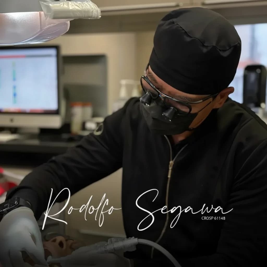 Dr. Rodolfo Segawa durante atendimento odontológico, utilizando equipamentos de magnificação.